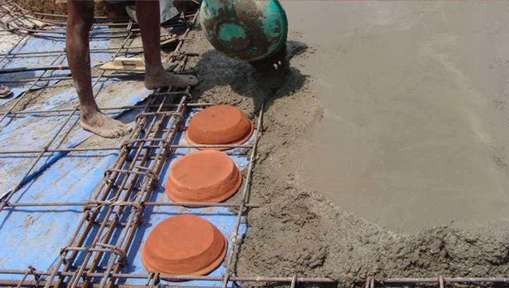 Pouring concrete for the filler-slab around inverted earthen pots. 
